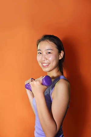 Young people exercise in the gym, using dumbbellsの写真素材