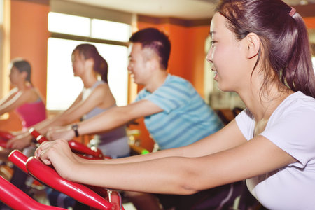 Group of four people spinning in the gym, exercising their legs doing cardio trainingの写真素材