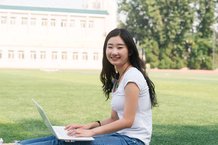 Beautiful Asian college student with laptop ,Sat on the playground.の写真素材