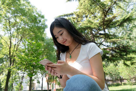 Closeup girl use a mobile phone in the parkの写真素材