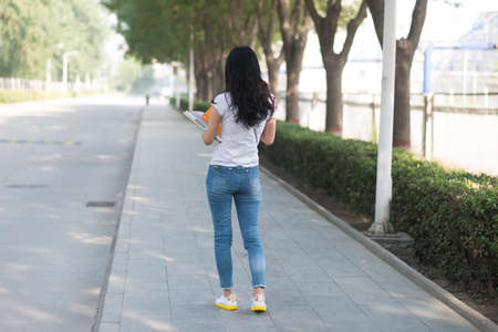 Girl holding the books in campus back viewの写真素材
