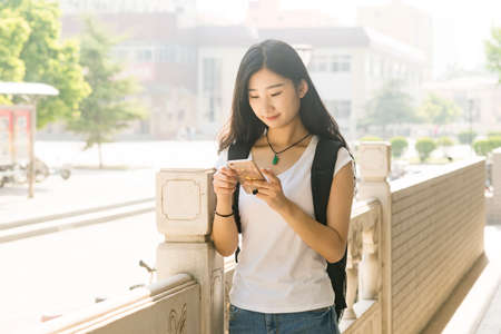 Asian female students using its ehrs smartphone in the campus corridorの写真素材