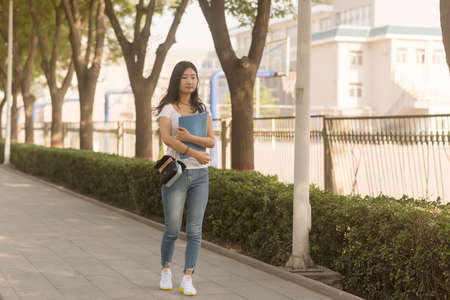 Girl carrying bag Walks in Campus Parkの写真素材