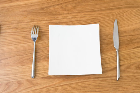 The knives and forks and empty plate on the table.