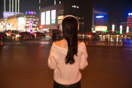 girl listen to music with headphones on city streets at nightの写真素材