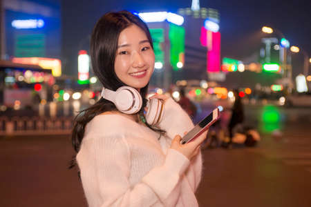 Beautiful woman talking on cellular telephone streets at nightの写真素材