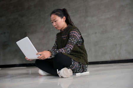 Asian female college students sitting on the floor using laptopsの写真素材