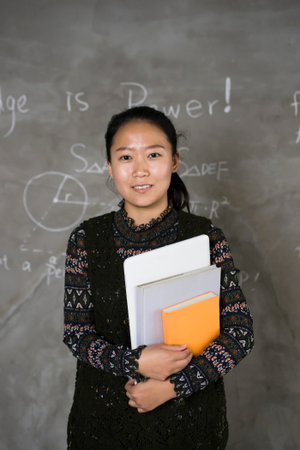 Confident female college students stand in front of the blackboard.