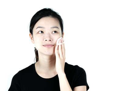 Asian girl applying cream lotion on face, isolated on white backgroundの写真素材