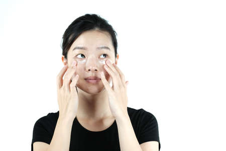 Asian girl applying cream lotion on face, isolated on white backgroundの写真素材