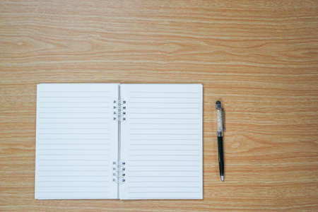 Blank notebook and a pen on wooden table with copyspaceの写真素材