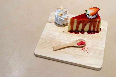 Strawberry cheesecake on wooden plate, focused on the cake surface, copy space on table backgroundの写真素材