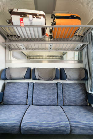 Three adjacent empty seats in modern European train with luggage on top, portrait orientationの写真素材