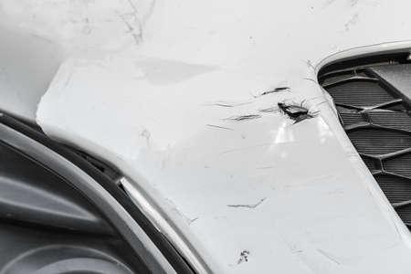 Dented wound and scratches on a damaged white carの写真素材