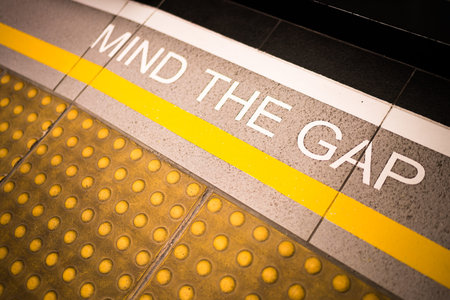Mind the gap sign painted on train station's platform edge, conceptual, vignette darken edge, depth of field blur on far endの写真素材
