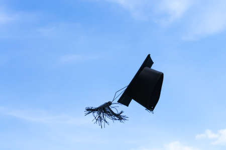One graduation cap or mortar board thrown up to the air, sky backgroundの写真素材