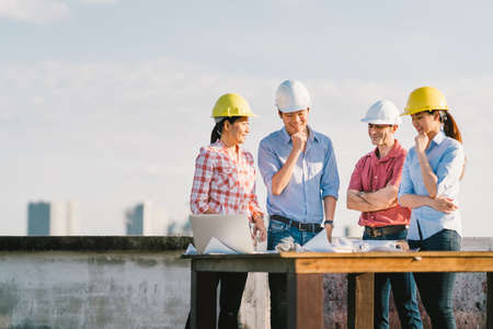 Multiethnic diverse group of engineers or business partners at construction site, working together on building's blueprint, architect industry or teamwork conceptの写真素材