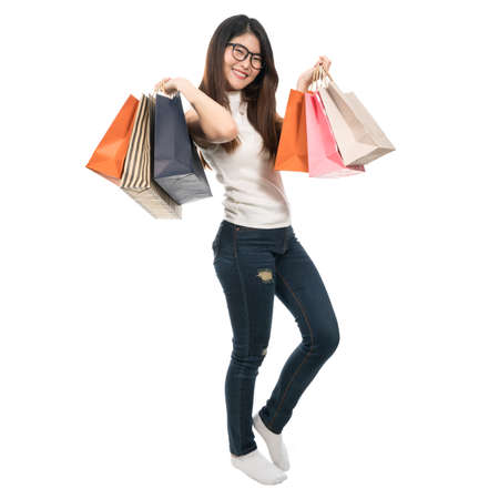 Beautiful Asian girl holding shopping bags on both hands, isolated on white background, lifestyle or shopaholic conceptの写真素材