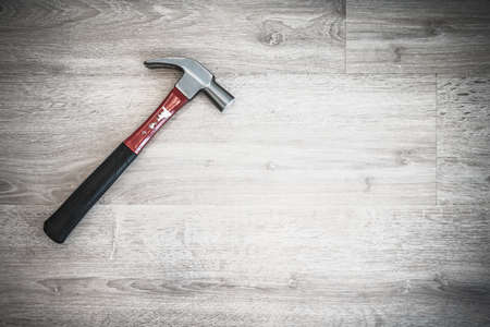 Red hammer on wooden floor, interior construction tool or home fixing renovation concept, dark tone abstract with vignette effectの写真素材