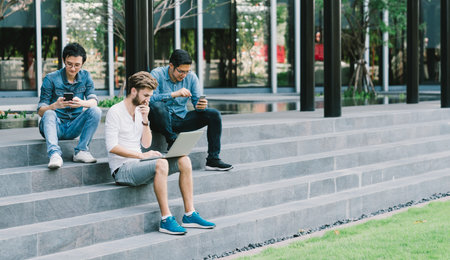 Multiethnic group of college students or freelance coworker using smartphone and laptop computer...