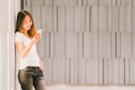 Young beautiful Asian girl or college student using smartphone and smiling. Modern lifestyle, mobile...