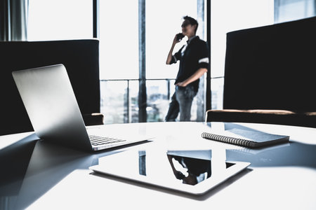 Male Asian small business owner using mobile phone call in modern office with laptop. Project management, Communication, information technology gadget, freelance, or startup SME entrepreneur conceptの写真素材