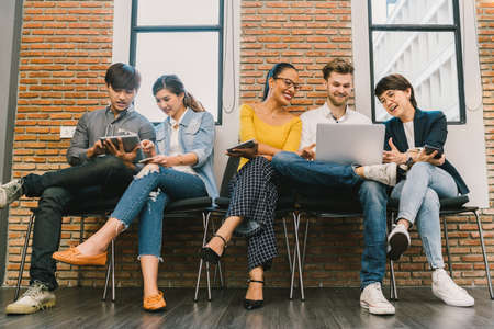 Multiethnic diverse group of young and adult people using smartphone, laptop computer, digital tablet together. Modern lifestyle with information technology gadget, education, social network conceptの写真素材