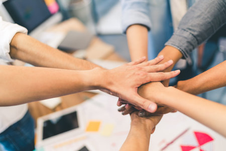 Business partners teamwork or friendship concept. Multiethnic diverse group of colleagues join hands...