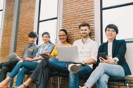 Multiethnic diverse group of young and adult people using smartphone, notebook computer, digital tablet together. Modern lifestyle with information technology gadget, education, social network conceptの写真素材