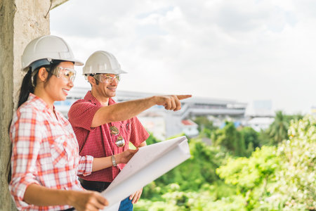 Multi-ethnic diverse couple of happy civil engineer working together on blueprint. Architect...