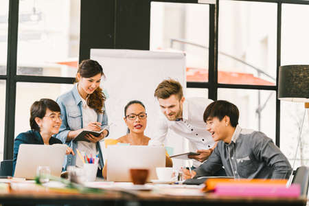 Multiethnic team busy discussion using laptop, digital tablet. Coworker partnership, college student meeting. Small business casual office, freelance designer job, or online marketing analysis conceptの写真素材