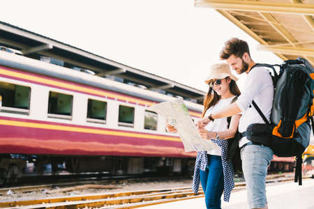 Multiethnic traveler couple, backpacker tourist, or college student using generic local map navigation together at train station platform. Asia tourism trip, outdoor backpack adventure travel conceptの写真素材