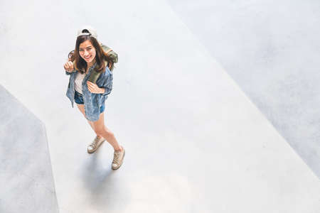 Young beautiful Asian backpack traveler, cute woman wearing hat looking up and smile, top view with copy space. Journey trip lifestyle, world travel explorer or Asia summer tropical tourism conceptの写真素材