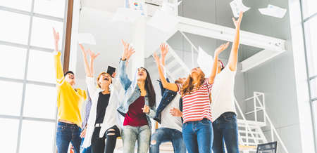 Multiethnic diverse happy team celebrate project success throw paper up together. Corporate community, college graduation, startup activity, salary raise promotion or successful small business conceptの写真素材