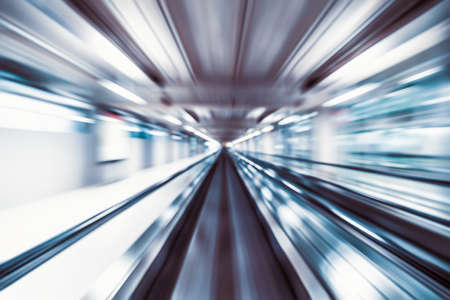 Motion blur abstract background, fast moving walkway or travelator in airport terminal transit, zoom effect, center diminishing perspective. Transportation, warp speed, or business technology conceptの写真素材