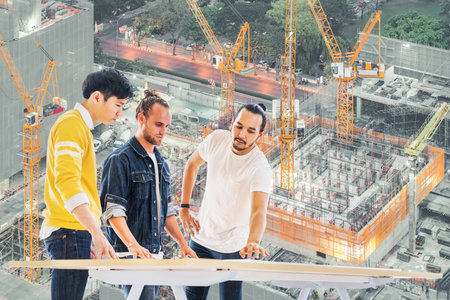 Three multiethnic engineers, architect team working together on building development project...
