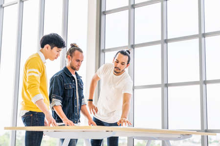 Multiethnic group of three men meeting discuss brainstorm project plan together, modern office with copy space. Small business startup, teamwork discussion, team building, or strategy planning conceptの写真素材