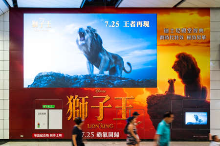 Hong Kong, Hong Kong - Jul 10, 2019: Lion King big movie poster and large TV screen showing movie trailer in public subway walkway. Cinema promotional advertisement, or film industry marketing conceptのeditorial素材