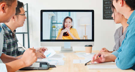Group of young Asian business people video conference with colleague woman. Remote vdo call meeting, coworker teamwork brainstorm, startup office company, or new normal lifestyle conceptの写真素材
