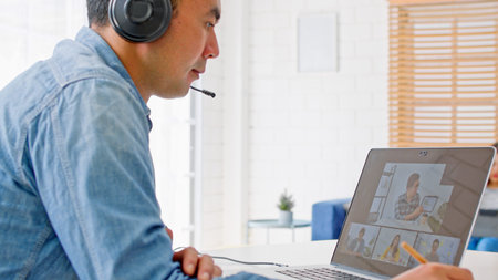 Young Asian man video call conference, online remote meeting with business coworker, at home in...