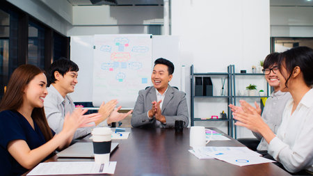 Group of happy Asian business people discuss together in team brainstorm meeting and clap hand, work...