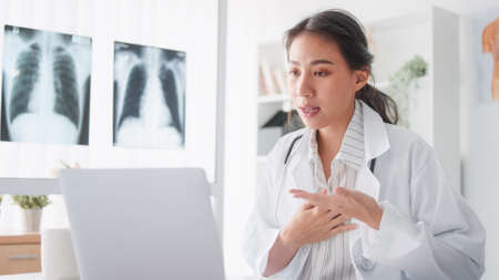 Asian female doctor using laptop computer online video call remote talking to patient, prescribe medicine. Tele medical, telehealth, hospital clinic health care service, or internet technology conceptの写真素材