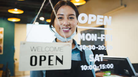 Portrait of Asian woman restaurant or coffee shop owner smile, hanging open sign post. Small business entrepreneur, Business reopen after covid-19 coronavirus pandemic, Covid relief lifestyle conceptの写真素材