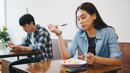 Young Asian men and women having lunch meals in a local restaurants, sit in social distance.