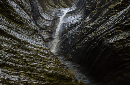 Waterfall the water is lit by the sunlight flows down the smooth wall of the canyonの写真素材
