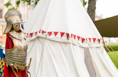 Medieval silver armor with a helmet is richly decorated with ornament on the background of a marching white tentの写真素材