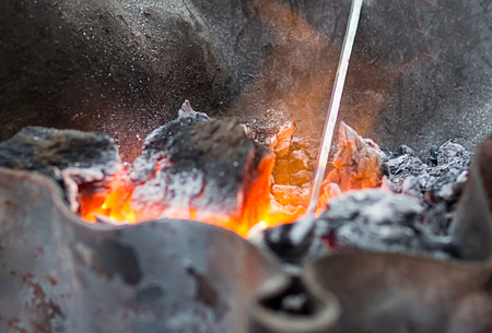 orange glowing coal covered with ash close up in an iron forgeの写真素材