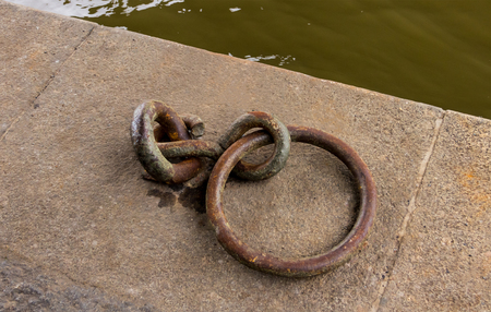 rusty ring iron hook anchorage for a boat on a stone beach canopy close-upの写真素材