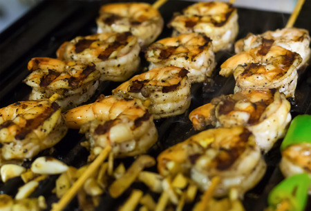 baked shrimp on a wooden skewer close-up with a grill stripes, light delicious appetizerの写真素材