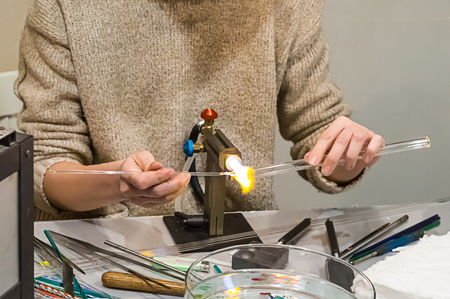 art manufacturing of glass jewelry products hands base tube blower, base heating melting gas burner handmadeの写真素材